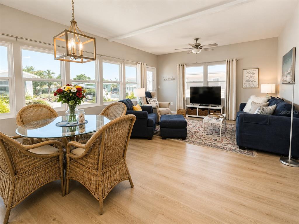 A bright living and dining area features light wood floors, wicker chairs, and blue furniture — 6621 MARINA DRIVE, BRADENTON, FL