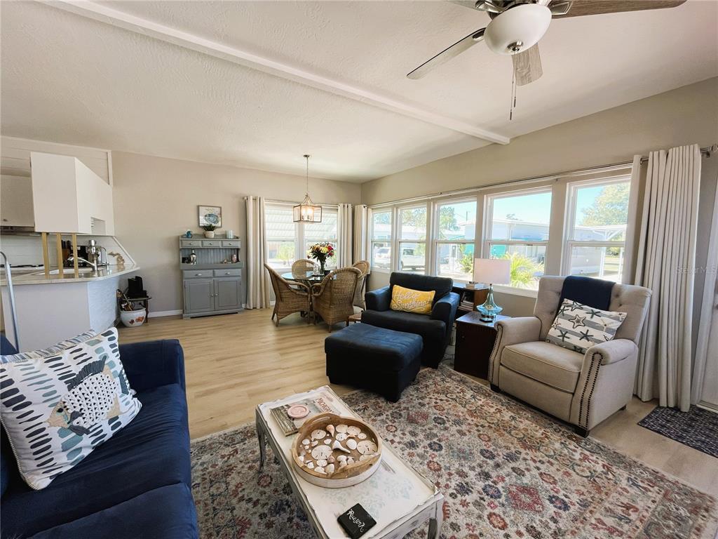 A living room with a blue sofa, armchairs, a dining area, and large windows — 6621 MARINA DRIVE, BRADENTON, FL