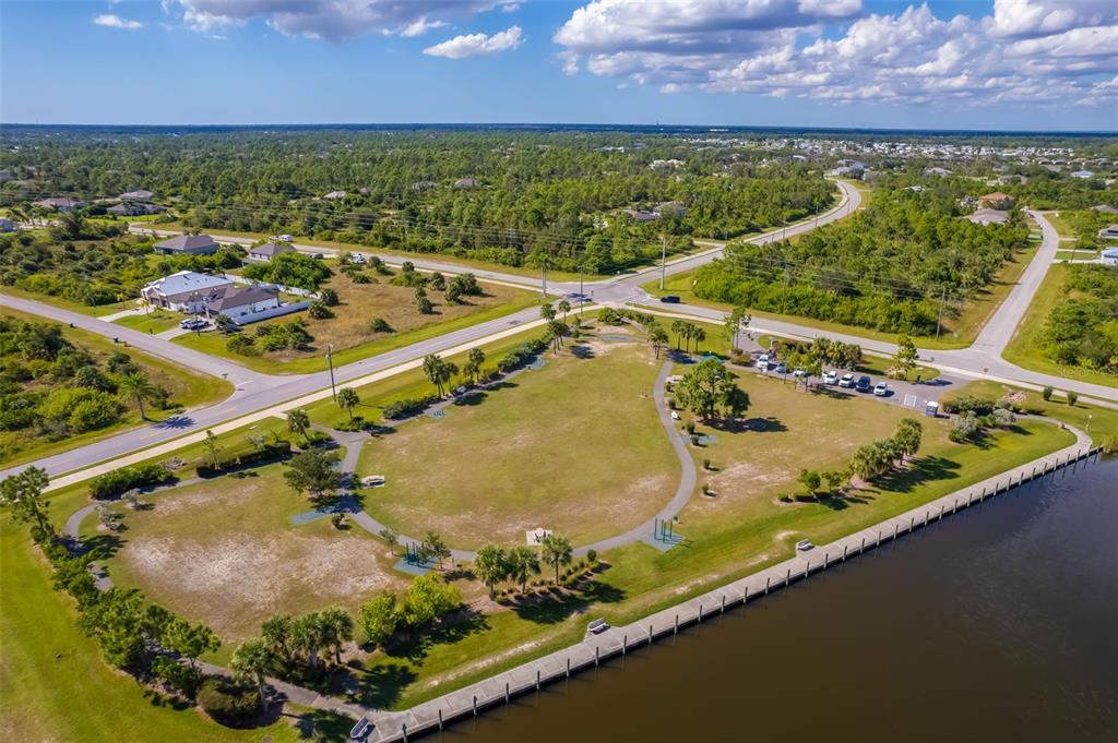 An aerial view shows a park with a walking path, green space, and a waterfront bulkhead — 10098 ARMY CIRCLE, PORT CHARLOTTE, FL