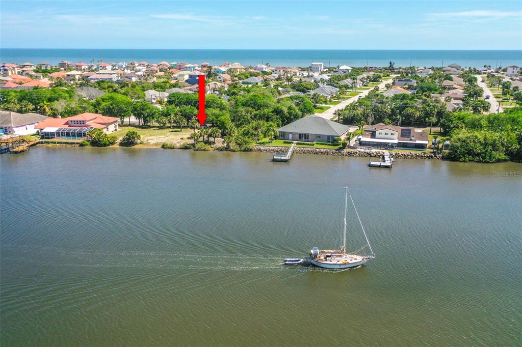 An aerial view shows a vacant waterfront lot marked by a red arrow — 3680 JOHN ANDERSON DR, ORMOND BEACH, FL