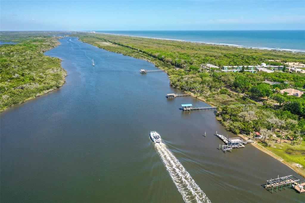 An aerial view shows a boat traveling down a river near a coastal shoreline — 3680 JOHN ANDERSON DR, ORMOND BEACH, FL