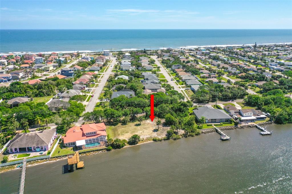 An aerial view shows a vacant waterfront lot marked by a red arrow — 3680 JOHN ANDERSON DR, ORMOND BEACH, FL