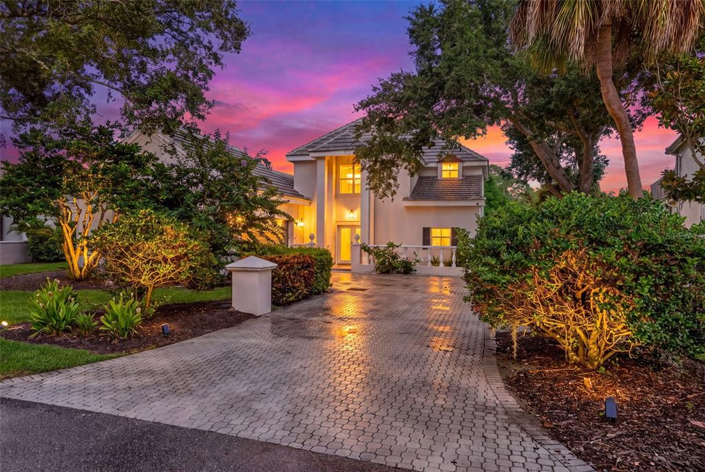 A two-story house with a paved driveway and illuminated landscaping at sunset — 226 SAINT JAMES PARK, OSPREY, FL