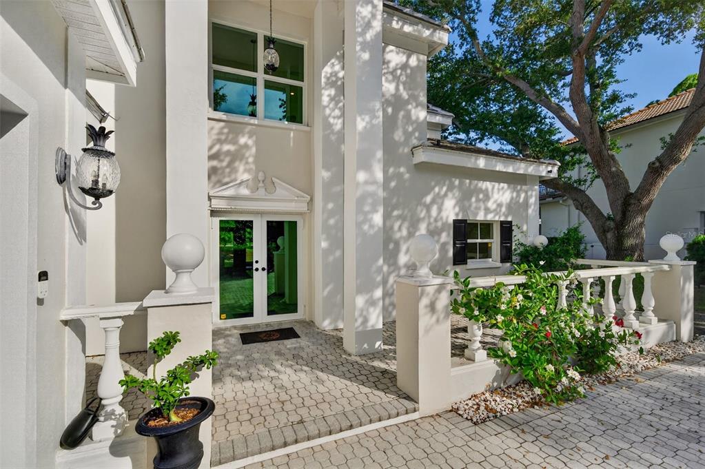 A paved entryway leads to a white house with double glass doors and stone railings — 226 SAINT JAMES PARK, OSPREY, FL