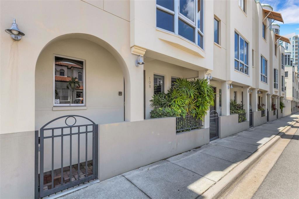A row of townhouses with arched entryways, metal gates, and light-colored stucco facades — 235 COCOANUT AVENUE UNIT 108B, SARASOTA, FL