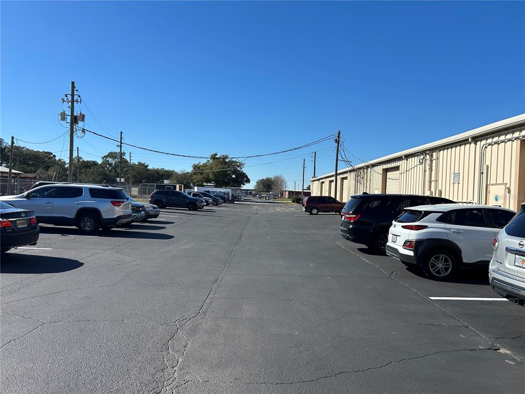 A parking lot with several vehicles parked alongside a long industrial building under clear skies — 5640 SW 6TH PLACE UNIT 300, OCALA, FL