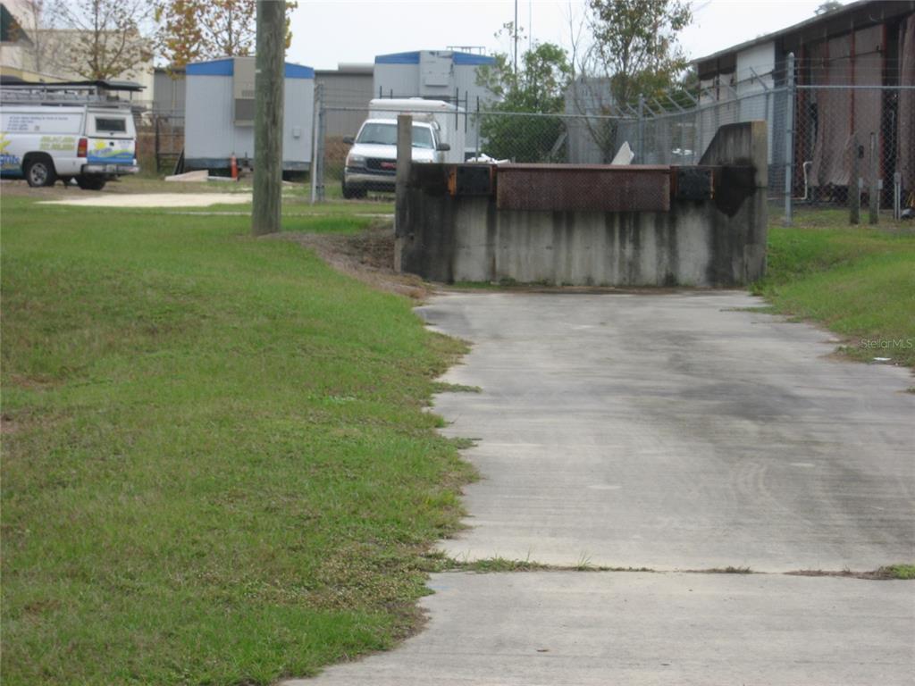 A concrete loading dock sits at the end of a paved driveway near a fence — 5640 SW 6TH PLACE UNIT 300, OCALA, FL