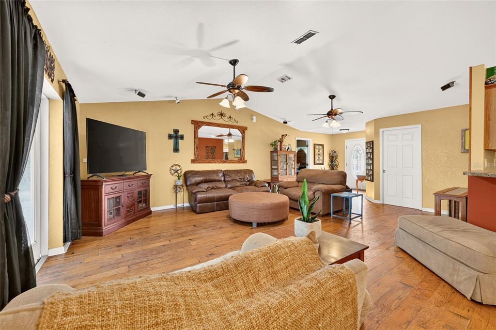 A living room with wood floors, two ceiling fans, brown furniture, and yellow walls — 14115 NE 47TH AVENUE, ANTHONY, FL