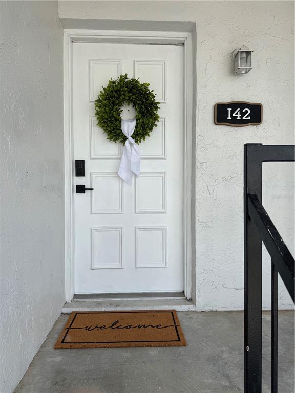 An entryway features wood-look flooring, a white door with a wreath, and a thermostat — 3819 N OAK DRIVE UNIT I42, TAMPA, FL