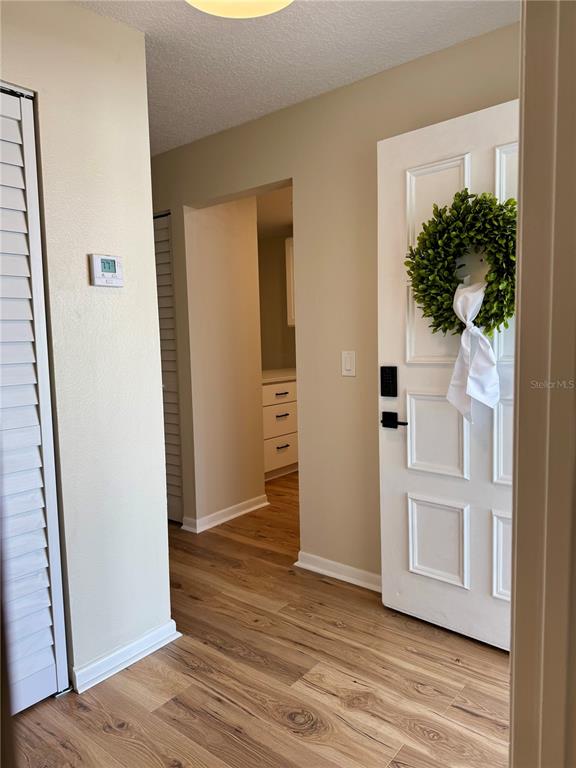 A living area with wood-look flooring leads to an open kitchen with white cabinets — 3819 N OAK DRIVE UNIT I42, TAMPA, FL