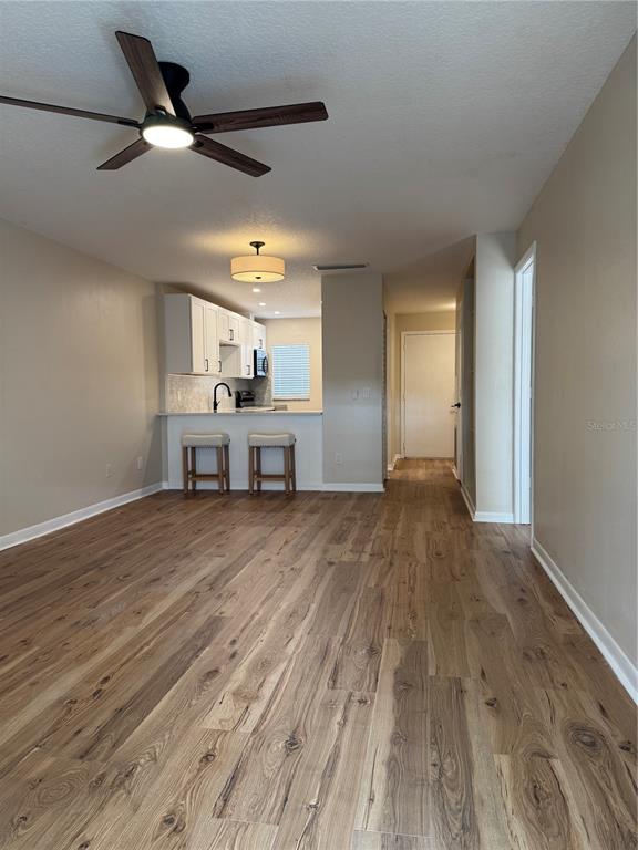 An empty living room features wood-look flooring, a ceiling fan, and a sliding glass door — 3819 N OAK DRIVE UNIT I42, TAMPA, FL