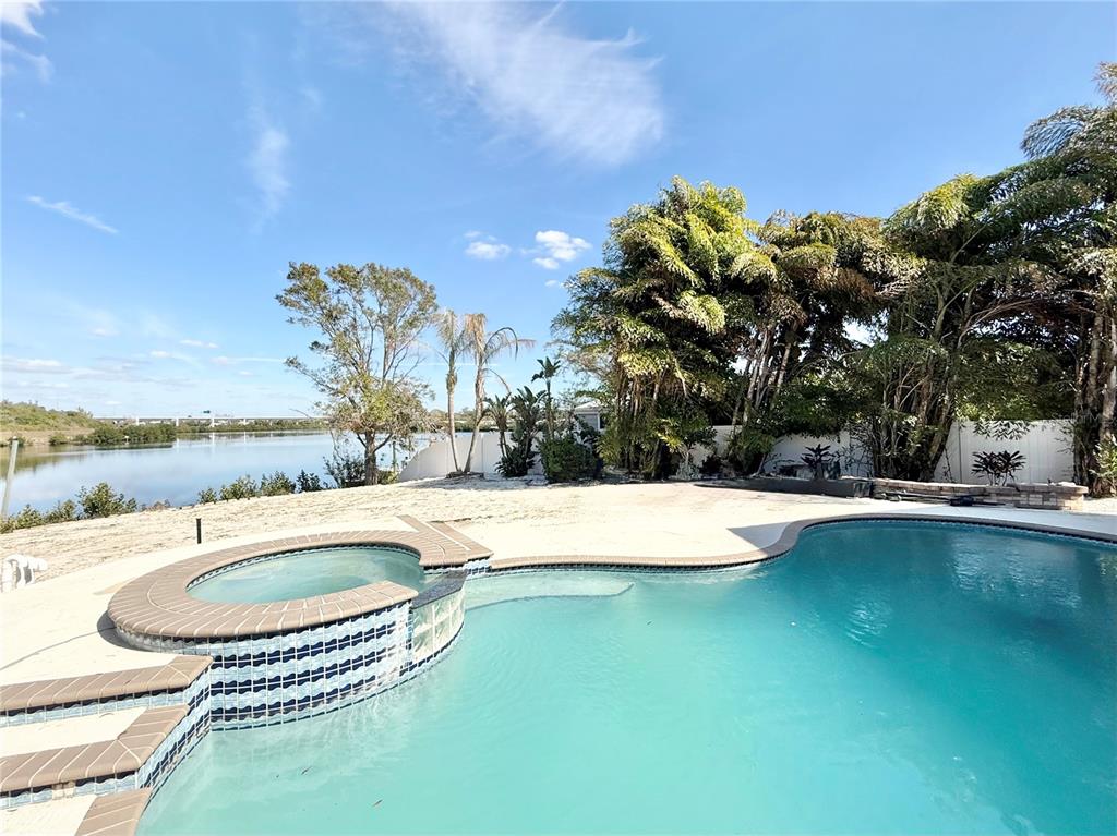 A swimming pool and attached hot tub sit on a patio overlooking a waterfront view — 6710 MYRNA DRIVE, TAMPA, FL
