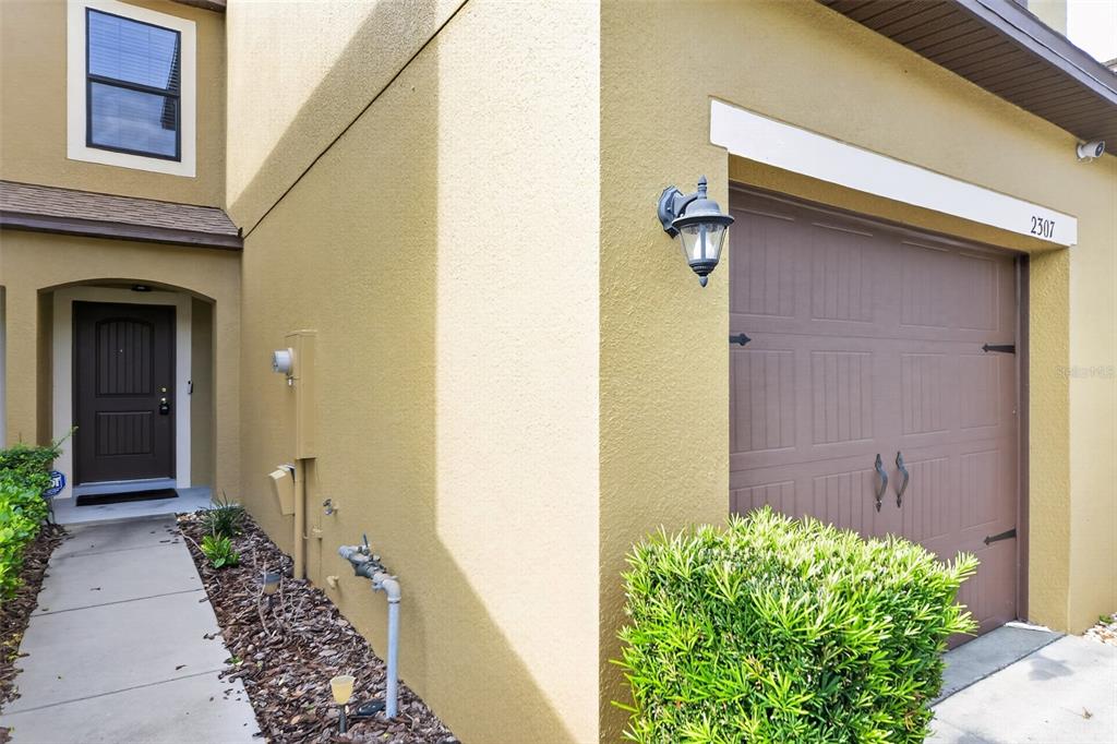 The exterior of a tan house features a brown front door and a single-car garage — 2307 ALOHA BAY COURT, OCOEE, FL