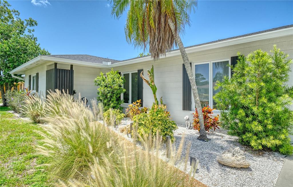 The exterior of a single-story house features light-colored siding, dark shutters, and a landscaped yard — 6926 ANTIGUA PLACE, SARASOTA, FL