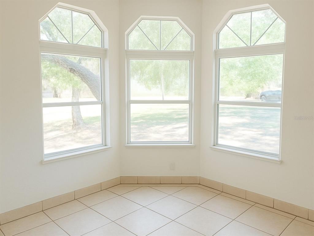 A sunlit breakfast nook features three large windows, white walls, and light-colored tiled flooring — 14640 NE 149TH LANE, FORT MC COY, FL