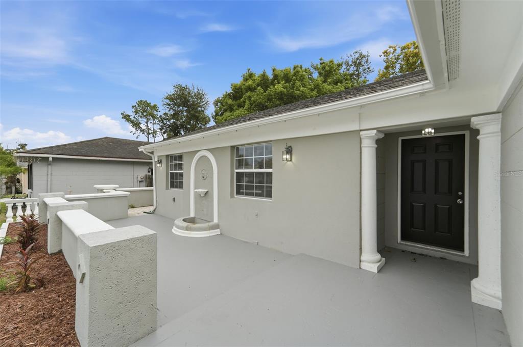 A gray patio features a wall-mounted fountain, white columns, and a black front door — 629 LA SALLE DRIVE, ALTAMONTE SPRINGS, FL