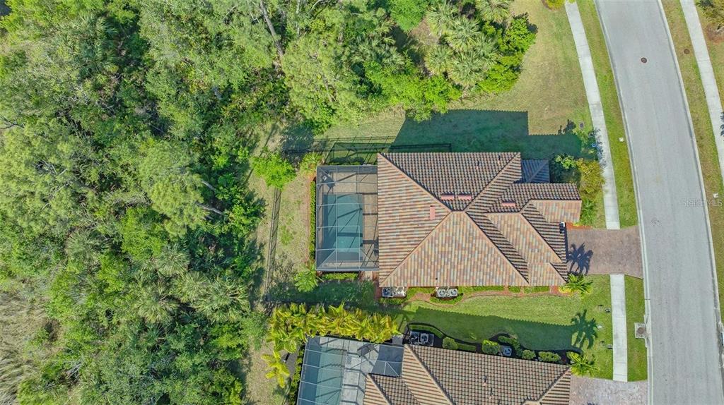 An aerial view shows a house with a screened-in pool and a tiled roof — 12801 CINQUETERRE DRIVE, VENICE, FL