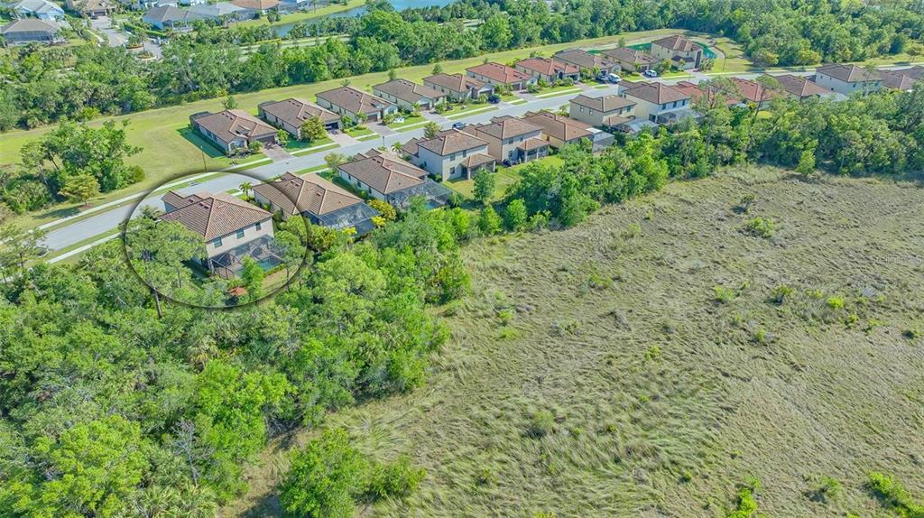 An aerial view shows a two-story house with a pool enclosure bordering a large field — 12801 CINQUETERRE DRIVE, VENICE, FL