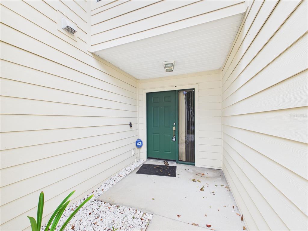 A green front door with a side window is set within a covered entryway — 11239 CEDAR HOLLOW LANE, TAMPA, FL