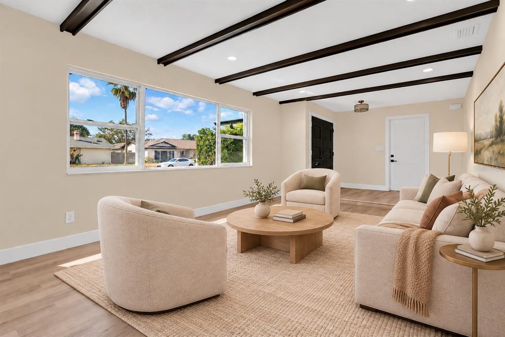 A living area with light wood flooring, dark ceiling beams, and an arched entryway — 330 ELKHORN COURT, WINTER PARK, FL