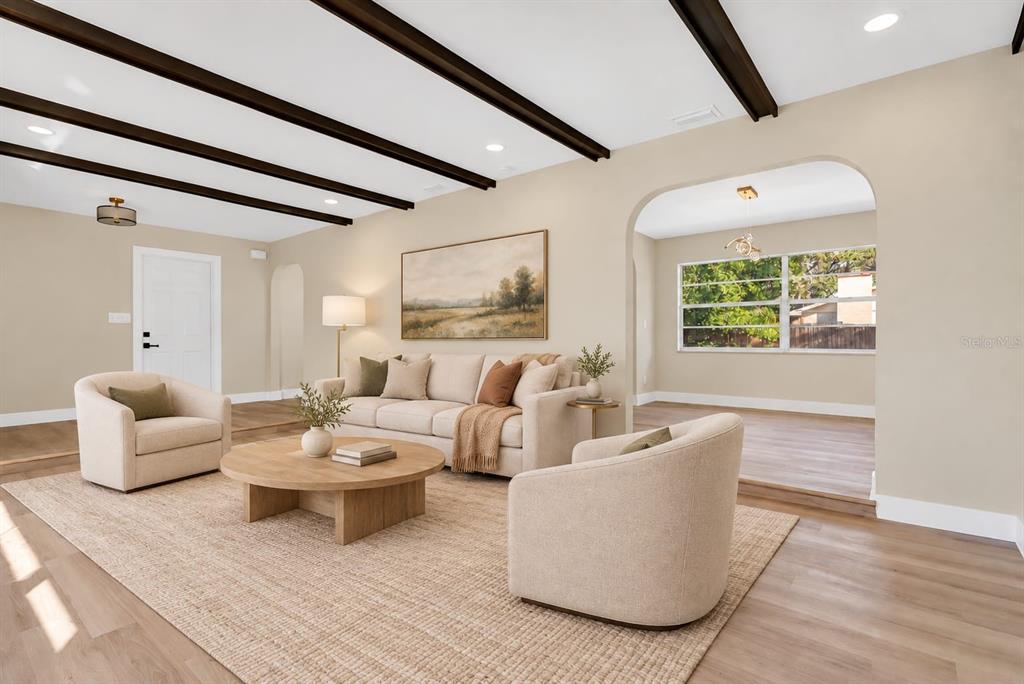 A bright living room features light wood-look flooring, dark ceiling beams, and a large window — 330 ELKHORN COURT, WINTER PARK, FL