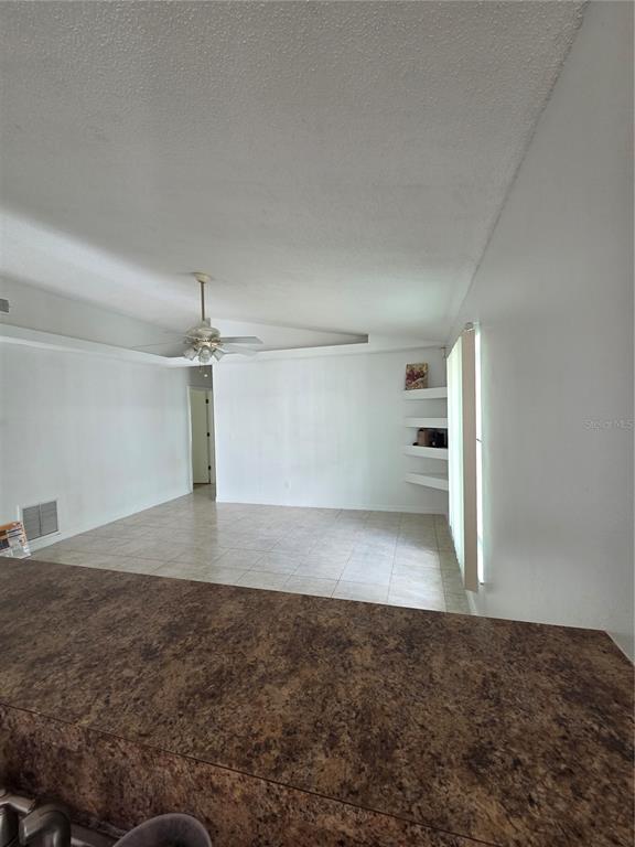 A view from a kitchen counter looking into an empty room with tiled floors — 1033 HAMLET DRIVE, MAITLAND, FL