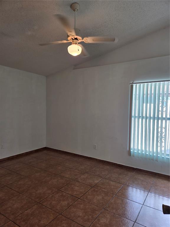 An empty room features white walls, brown tile flooring, a ceiling fan, and vertical blinds — 1033 HAMLET DRIVE, MAITLAND, FL