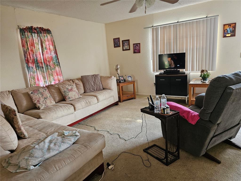A living room features a beige sectional sofa, a gray recliner, and a television console — 320 COUNTY ROAD 619, LAKE PLACID, FL