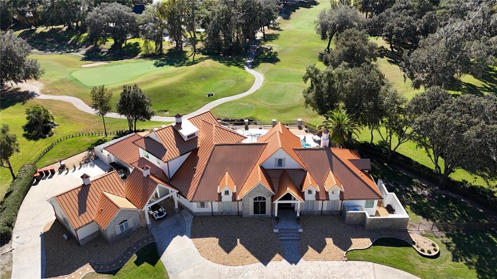 An aerial view of a large house with a copper-colored metal roof near a golf course — 7387 SE 12TH CIRCLE, OCALA, FL