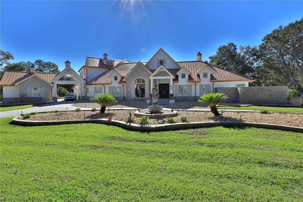 A large, multi-gabled house with a metal roof, stone facade, and a front yard fountain — 7387 SE 12TH CIRCLE, OCALA, FL