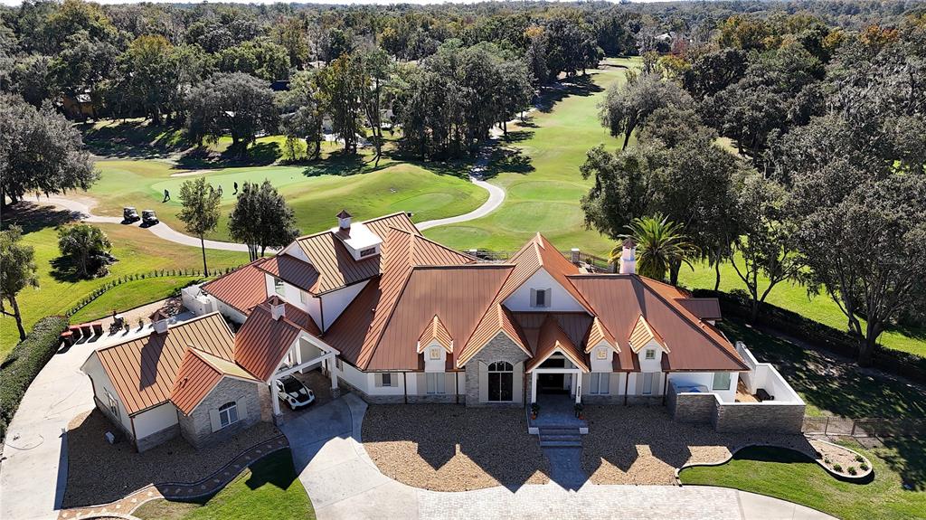 An aerial view of a large house with a copper roof overlooking a golf course — 7387 SE 12TH CIRCLE, OCALA, FL