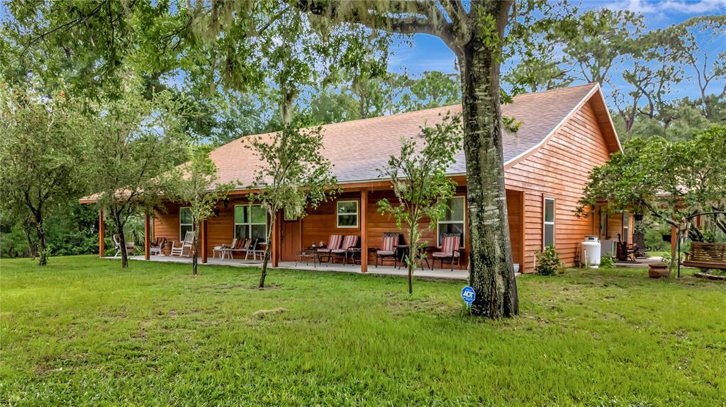 A one-story wooden house with a covered front porch sits on a grassy lawn — 7427 REDWING ROAD, GROVELAND, FL