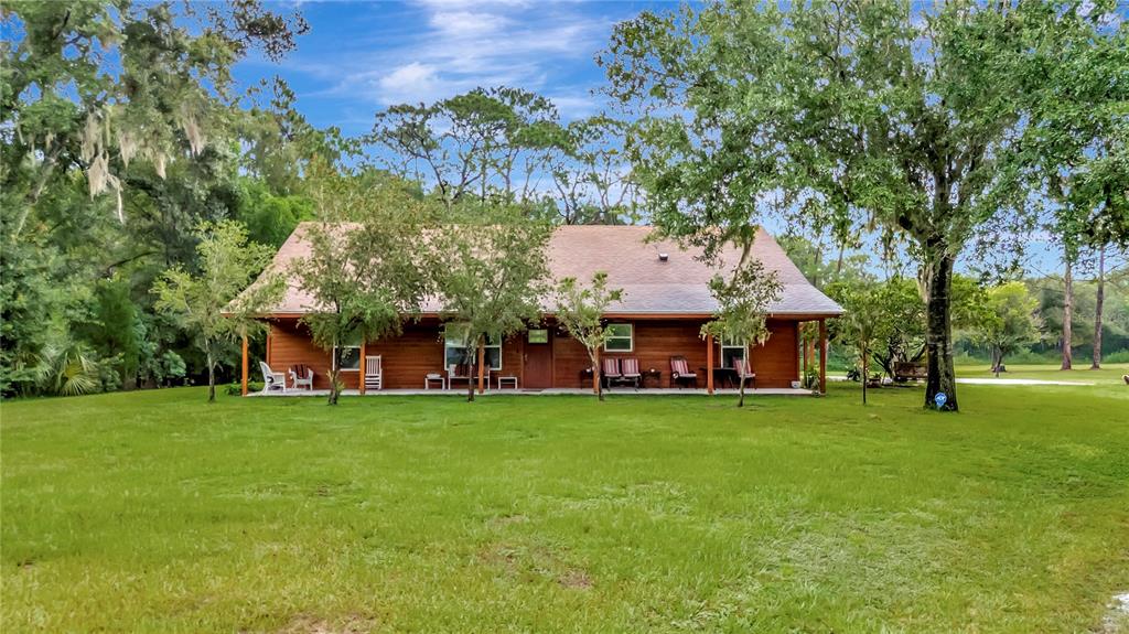 A single-story wooden house with a covered front porch sits on a grassy lawn — 7427 REDWING ROAD, GROVELAND, FL