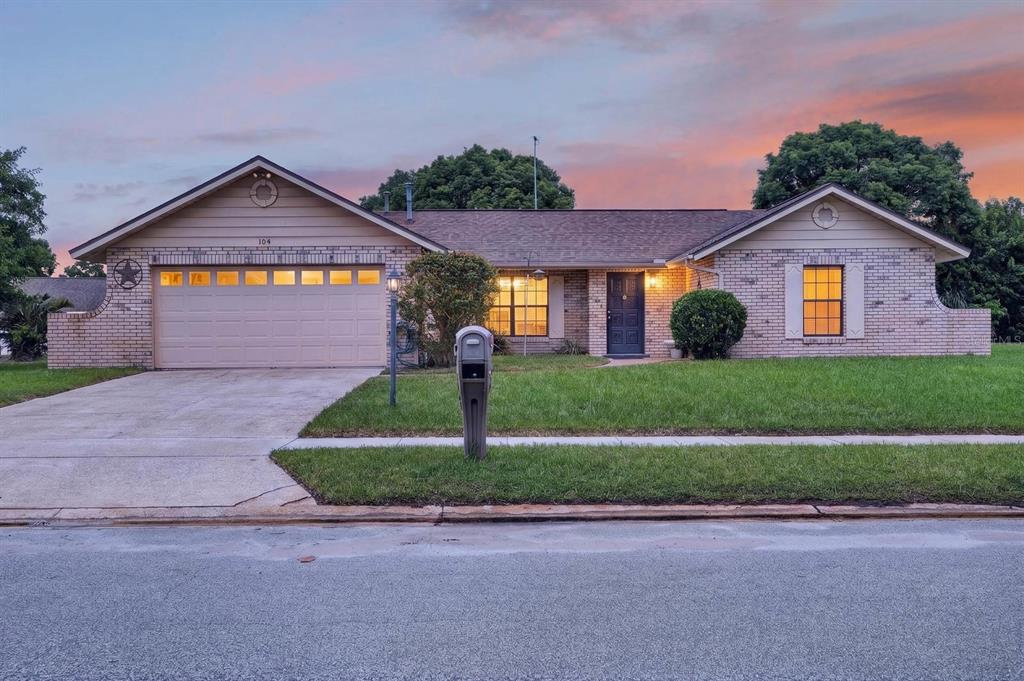A single-story brick house with a two-car garage and a front lawn at sunset — 104 COLLEEN DRIVE, DAYTONA BEACH, FL
