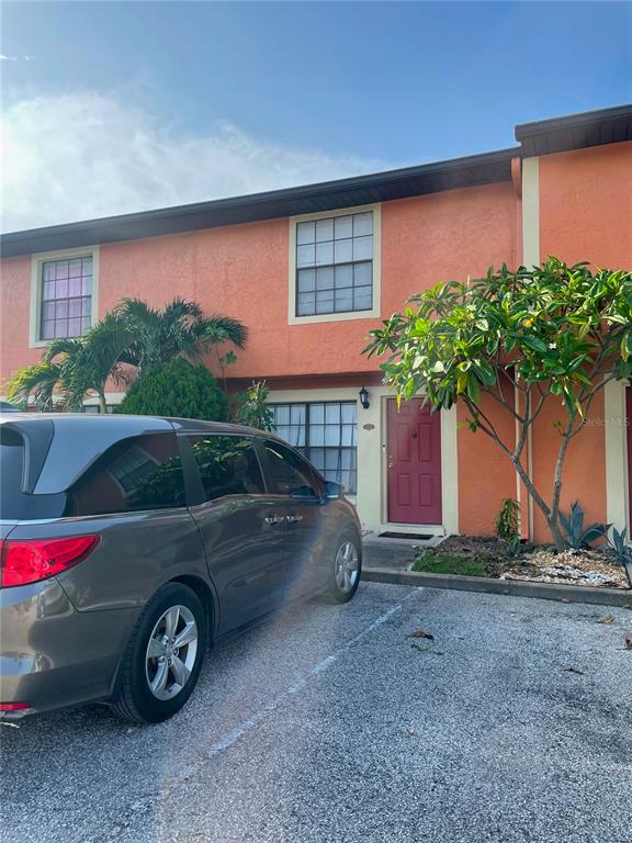 A two-story orange townhouse exterior features a red front door and a parked minivan — 7327 FOREST HILL COURT UNIT 223, WINTER PARK, FL