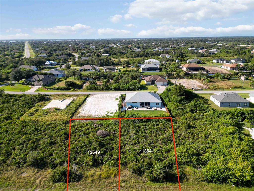 An aerial view shows two adjacent vacant lots outlined in red next to a house — 13549 ABUTILON LANE, PORT CHARLOTTE, FL