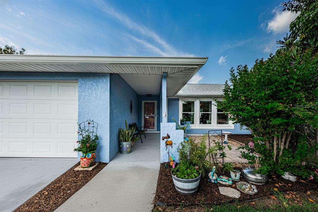 The exterior of a blue house features a garage, a covered entryway, and a front patio — 1886 ARGILE DRIVE, DUNEDIN, FL