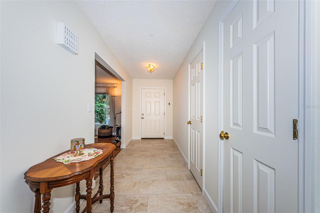 A hallway with light tile flooring, white walls, and two closed doors on the right — 1886 ARGILE DRIVE, DUNEDIN, FL