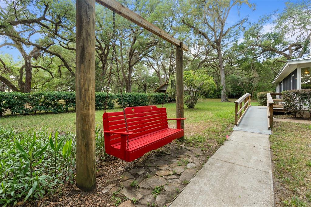 A house with a metal roof and screened porch sits behind a curved concrete driveway — 1153 CR 722, WEBSTER, FL