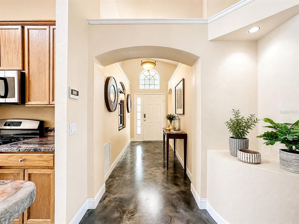 A view from a kitchen looking into a foyer with an arched entryway and flooring — 7116 COLONY POINTE DRIVE, RIVERVIEW, FL