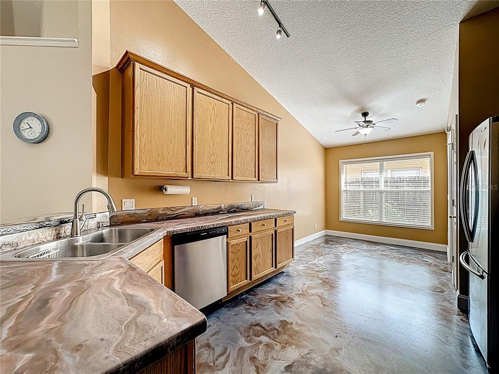 A kitchen features oak cabinets, a marbled countertop, and a glossy, patterned epoxy floor — 7116 COLONY POINTE DRIVE, RIVERVIEW, FL