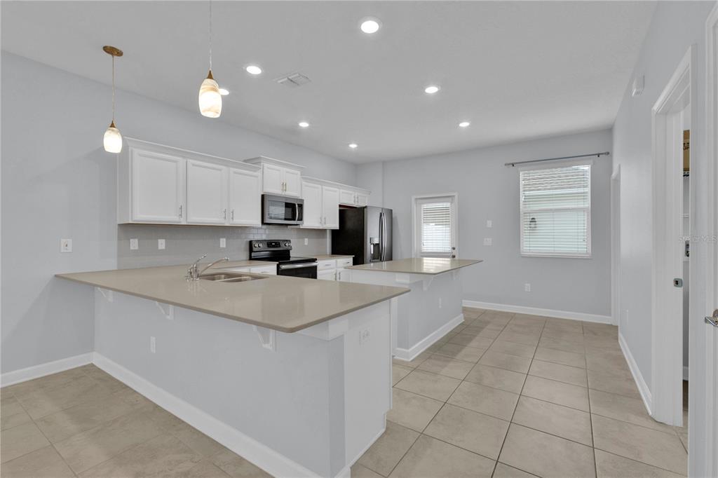 A kitchen features white cabinets, light countertops, a kitchen island, and tile flooring — 11048 SUSPENSE DRIVE, WINTER GARDEN, FL