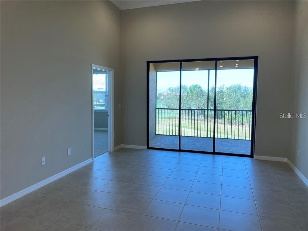 A room with tile flooring, high ceilings, and a sliding glass door leading to a balcony — 13823 MESSINA LOOP UNIT 203, BRADENTON, FL