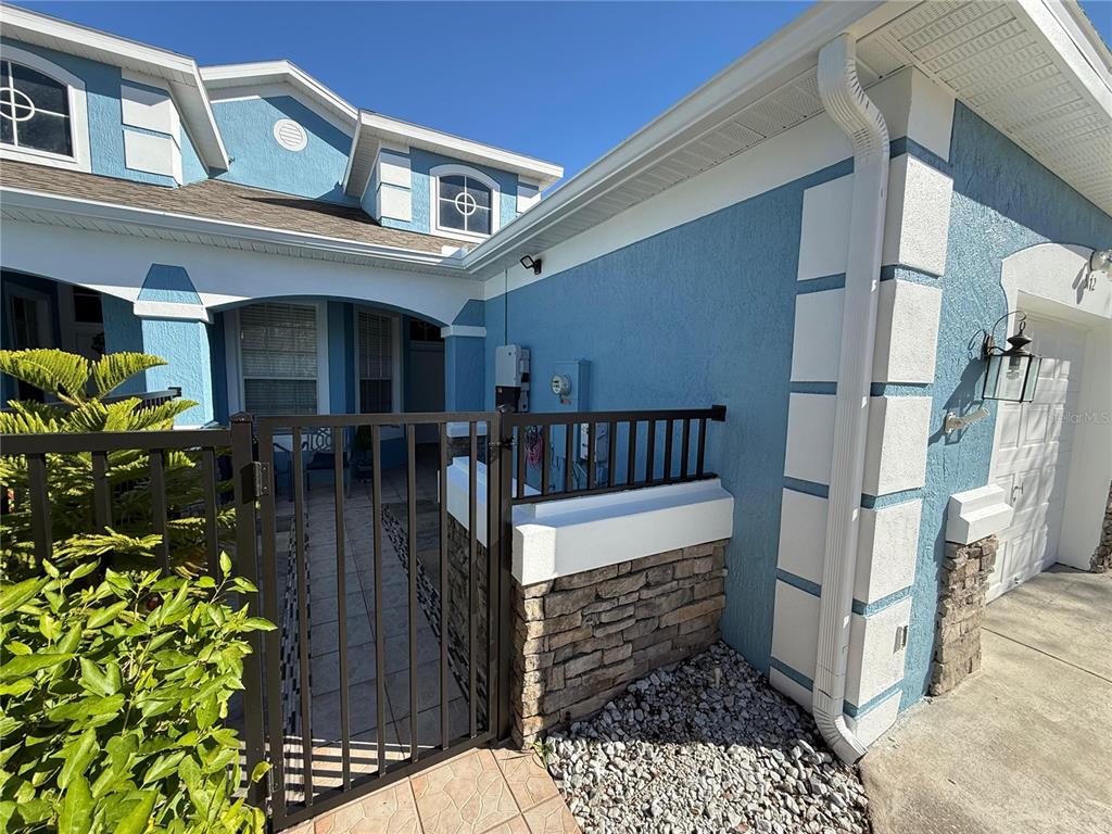 A blue house exterior features a gated courtyard entrance with stone accents and white trim — 3172 RIVER BRANCH CIRCLE, KISSIMMEE, FL