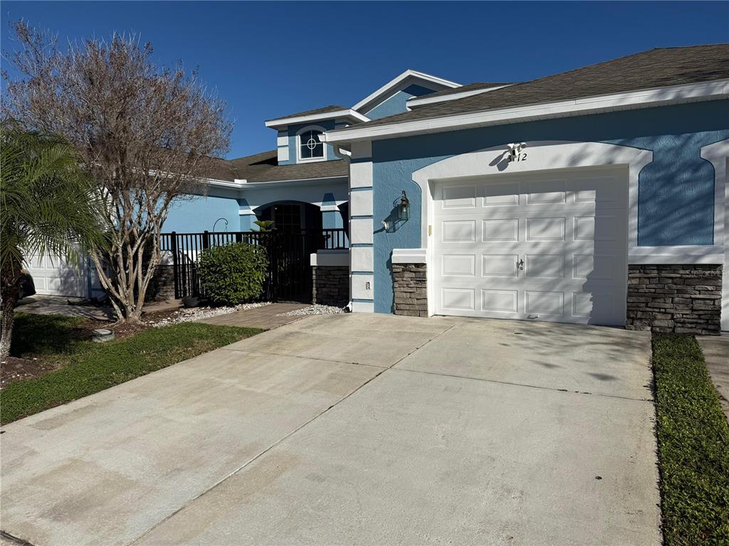 A blue house with a white garage door, stone accents, and a paved driveway — 3172 RIVER BRANCH CIRCLE, KISSIMMEE, FL