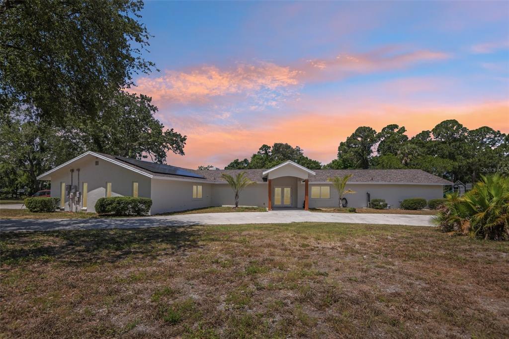 A single-story house with a concrete driveway, solar panels, and a central covered entryway — 11295 131ST STREET, LARGO, FL