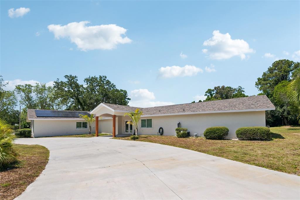 A single-story house with a concrete driveway, solar panels, and a covered entryway — 11295 131ST STREET, LARGO, FL