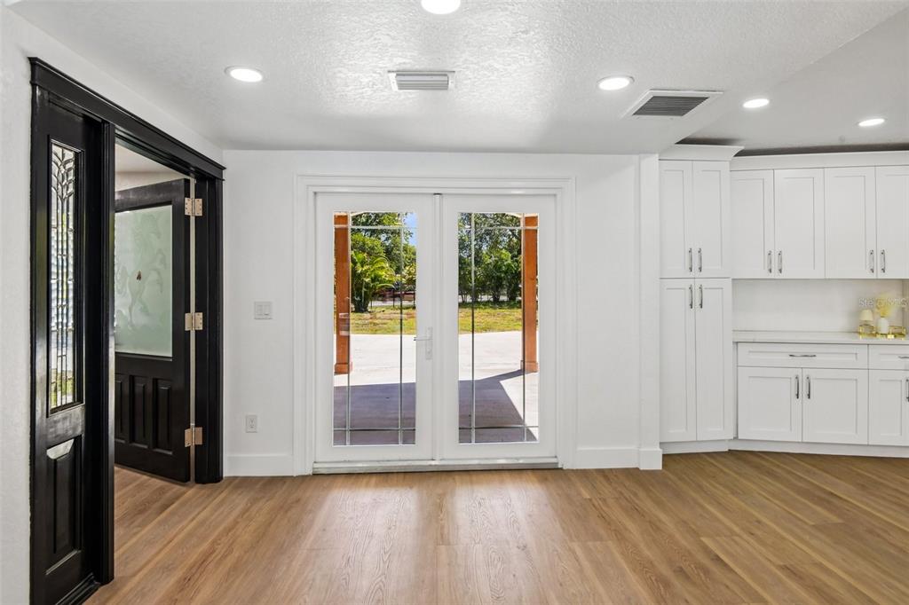 A room with light wood flooring, white cabinets, and French doors leading to a patio — 11295 131ST STREET, LARGO, FL