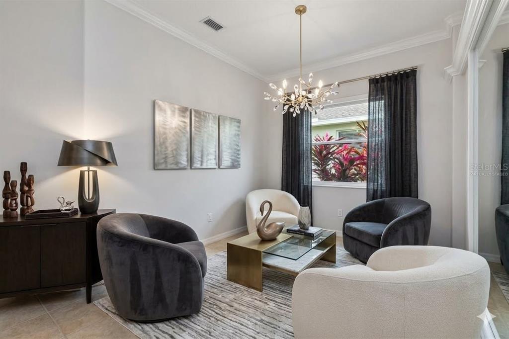 A bright, open-concept living and dining area features tile flooring, neutral furniture, and large windows — 8150 INDIGO RIDGE TERRACE, UNIVERSITY PARK, FL
