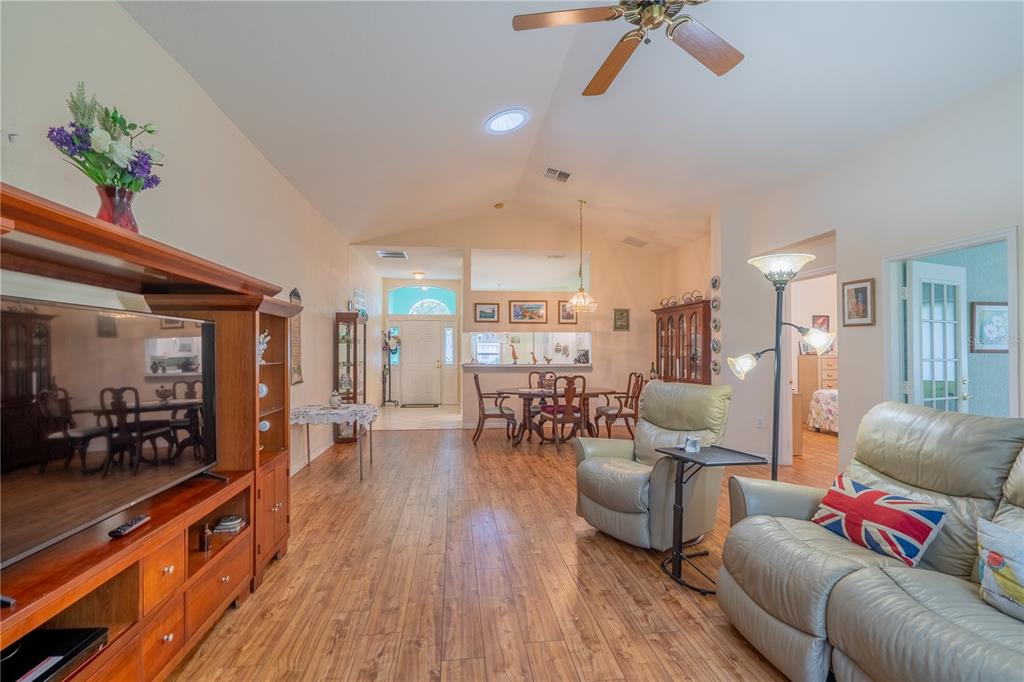 A living room with wood-look flooring, a vaulted ceiling, and an open dining area — 10971 SW 69TH CIRCLE, OCALA, FL